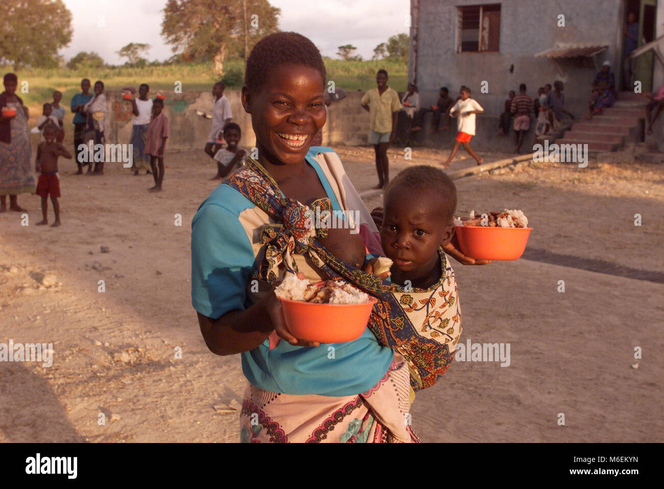 Inondazioni in Mozambico marzo 2000; una giovane madre felice di avere ricevuto cotte ciotole di riso e stufato preparato con rilievo fornisce in Pande camp per le vittime delle inondazioni vicino a salvare la città. Foto Stock