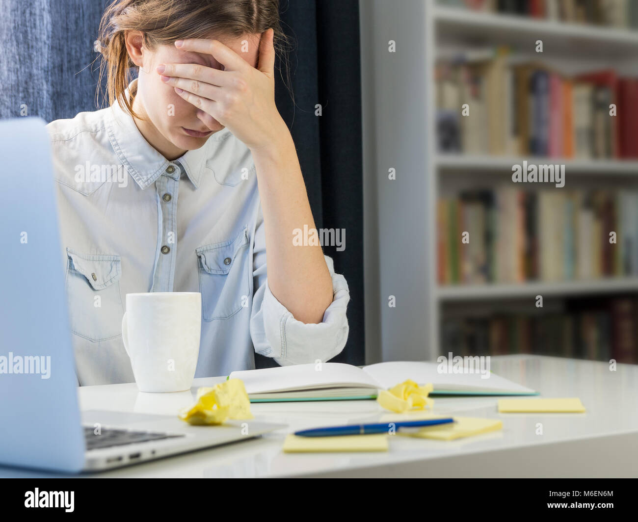 Stanco o esaurito persona seduta alla scrivania Foto Stock