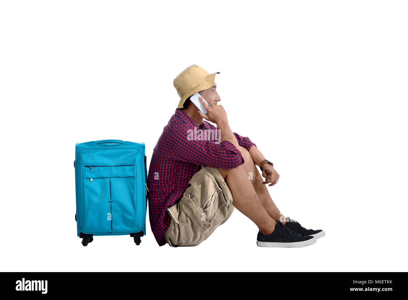 Ritratto di viaggio in Asia uomo seduto accanto a valigia e parlando al telefono cellulare in posa isolate su sfondo bianco Foto Stock