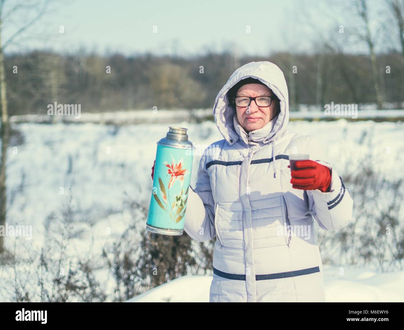 Caucasian donna di mezza età drimking tea sullo sfondo di una coperta di neve campo e foresta Foto Stock