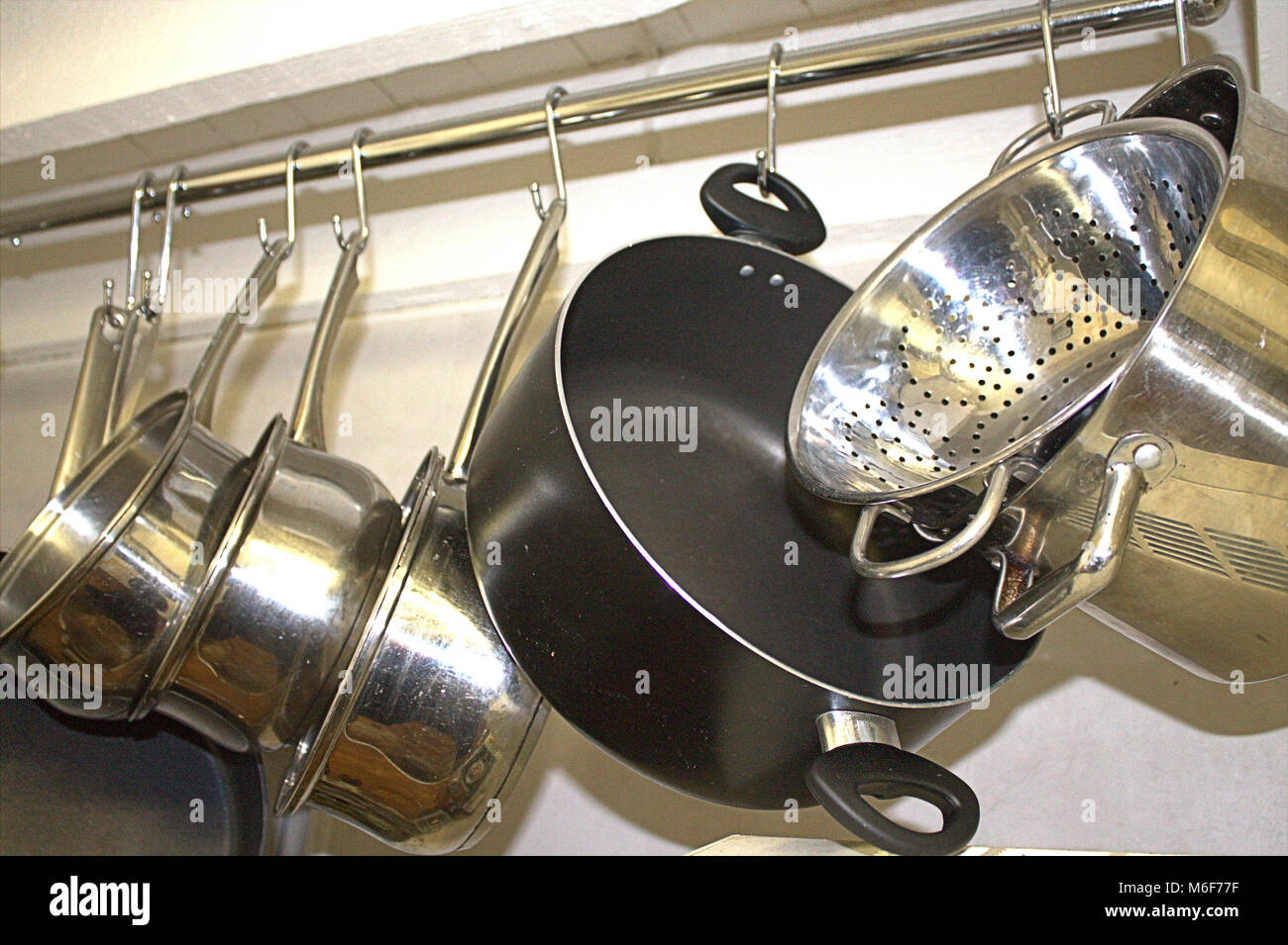 Pentole e padelle appesi su una rotaia in una cucina domestica Foto Stock