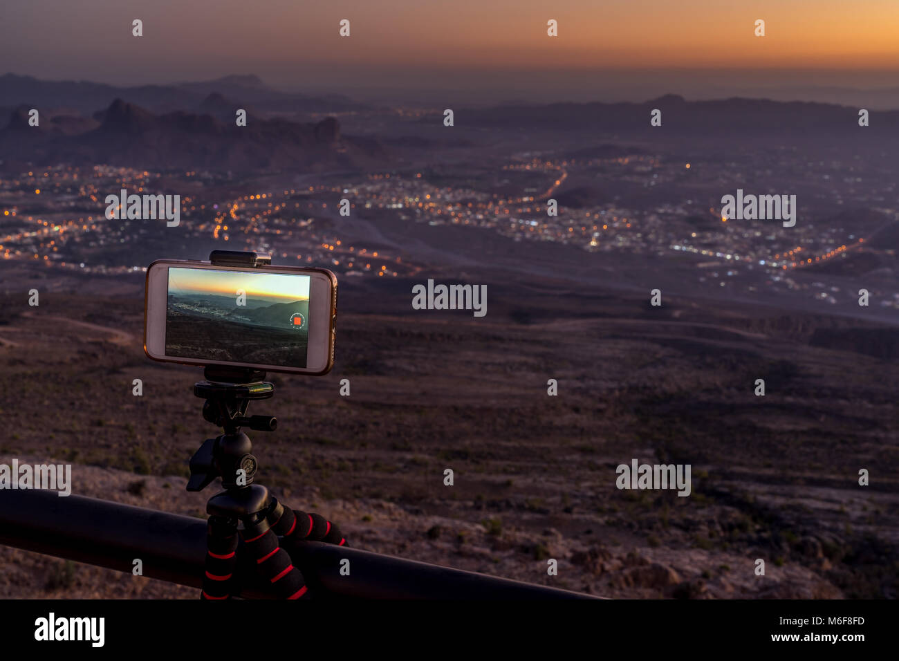 Cellulare montato sulla rampa tenendo timelap video dell'illuminato Al Hamra Village al tramonto Foto Stock