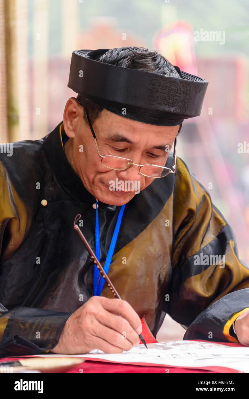 Un uomo vietnamita utilizza un pennello per disegnare i caratteri cinesi calligraphy ad Hanoi, Vietnam Foto Stock