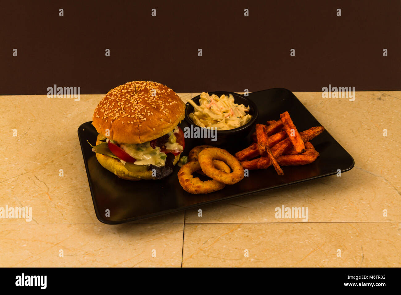 Carni bovine Gourmet Burger, con insalata, blu salsa al formaggio, patata dolce patate fritte, anelli di cipolla e coleslaw Foto Stock