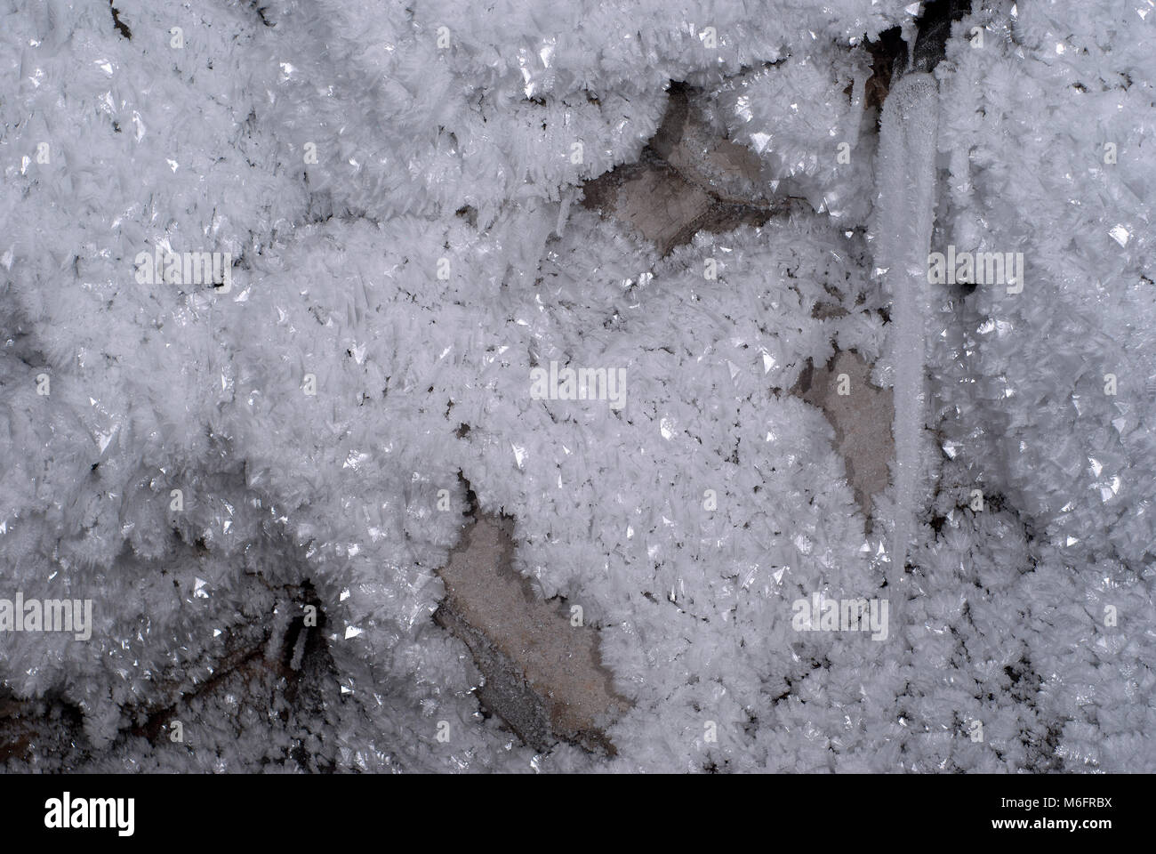 Grandi cristalli di ghiaccio sul muro di pietra della grotta sotterranea Foto Stock