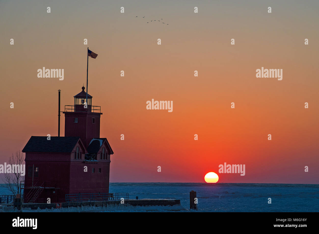 Michigan faro rosso sul Lago Michigan pier in inverno al tramonto Foto Stock