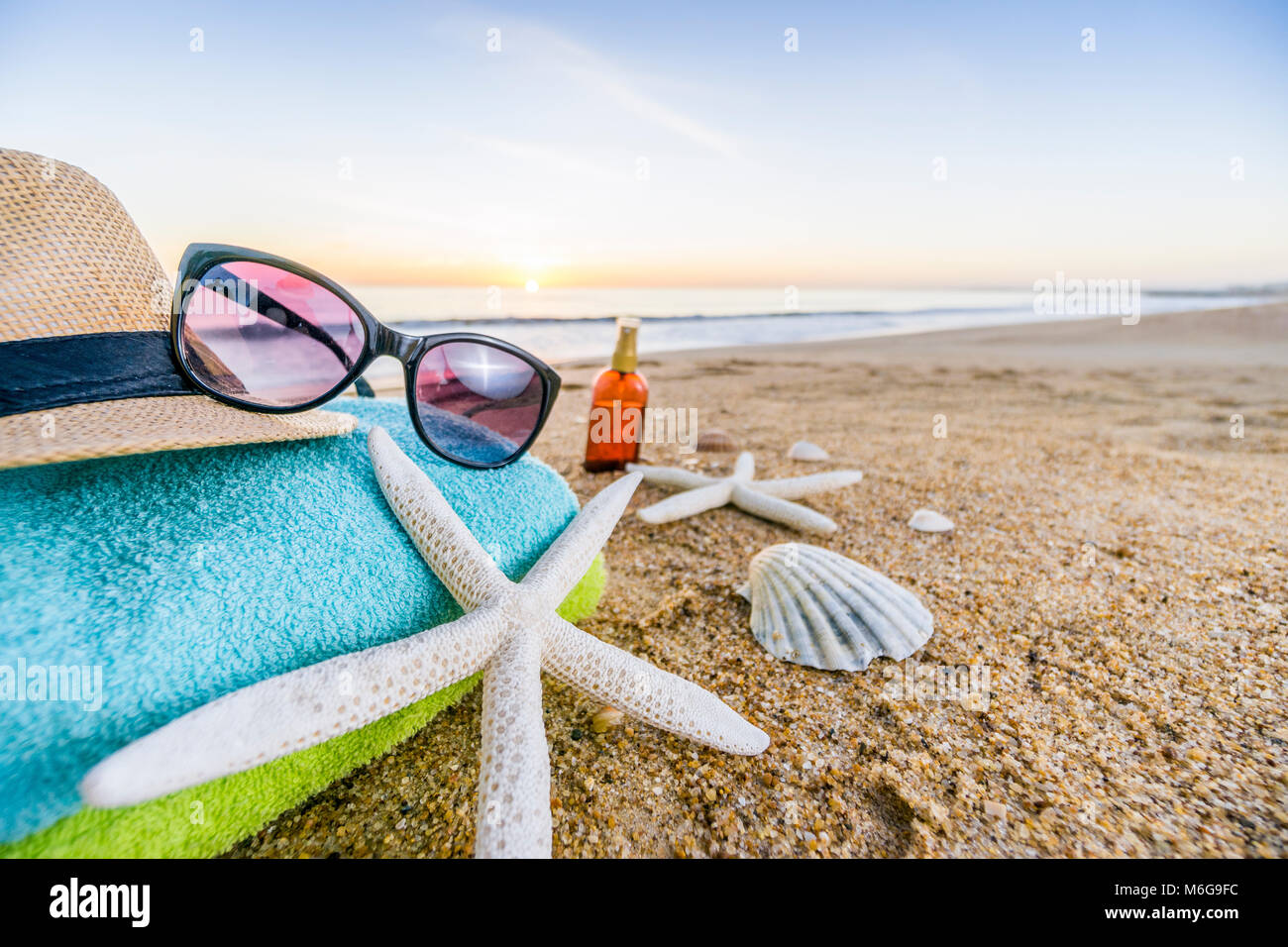 Estate accessori come occhiali da sole, asciugamani, cappello, solare,  conchiglie e stella di mare sulla spiaggia di sabbia in Portogallo Foto  stock - Alamy