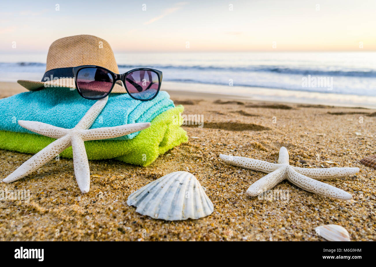 Estate accessori come occhiali da sole, asciugamani, cappello, solare,  conchiglie e stella di mare sulla spiaggia di sabbia in Portogallo Foto  stock - Alamy