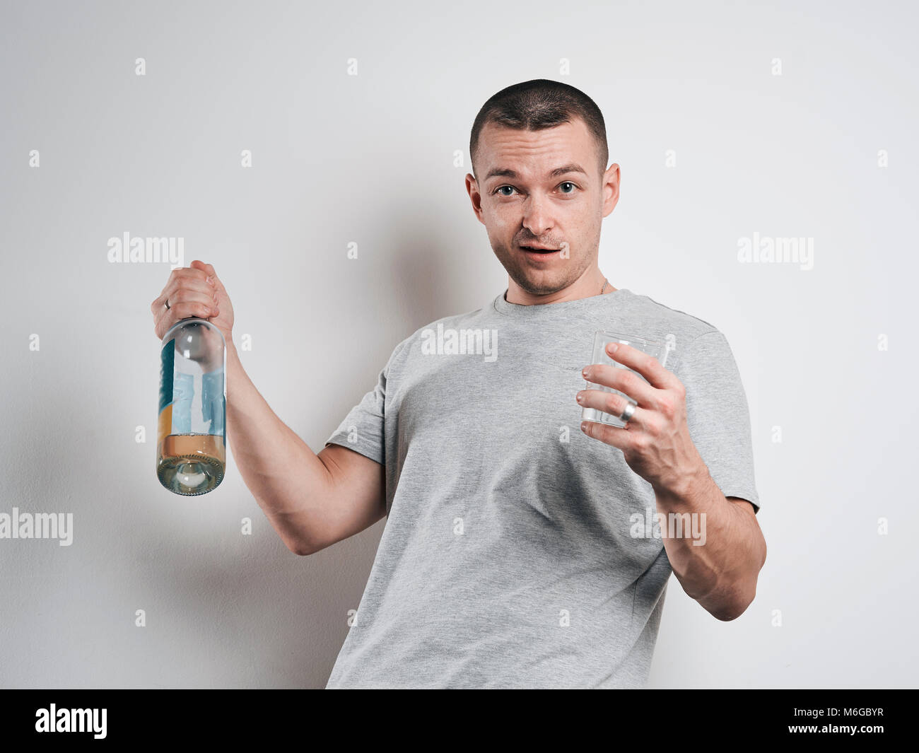 Divertenti uomo ubriaco con una bottiglia su sfondo bianco Foto Stock