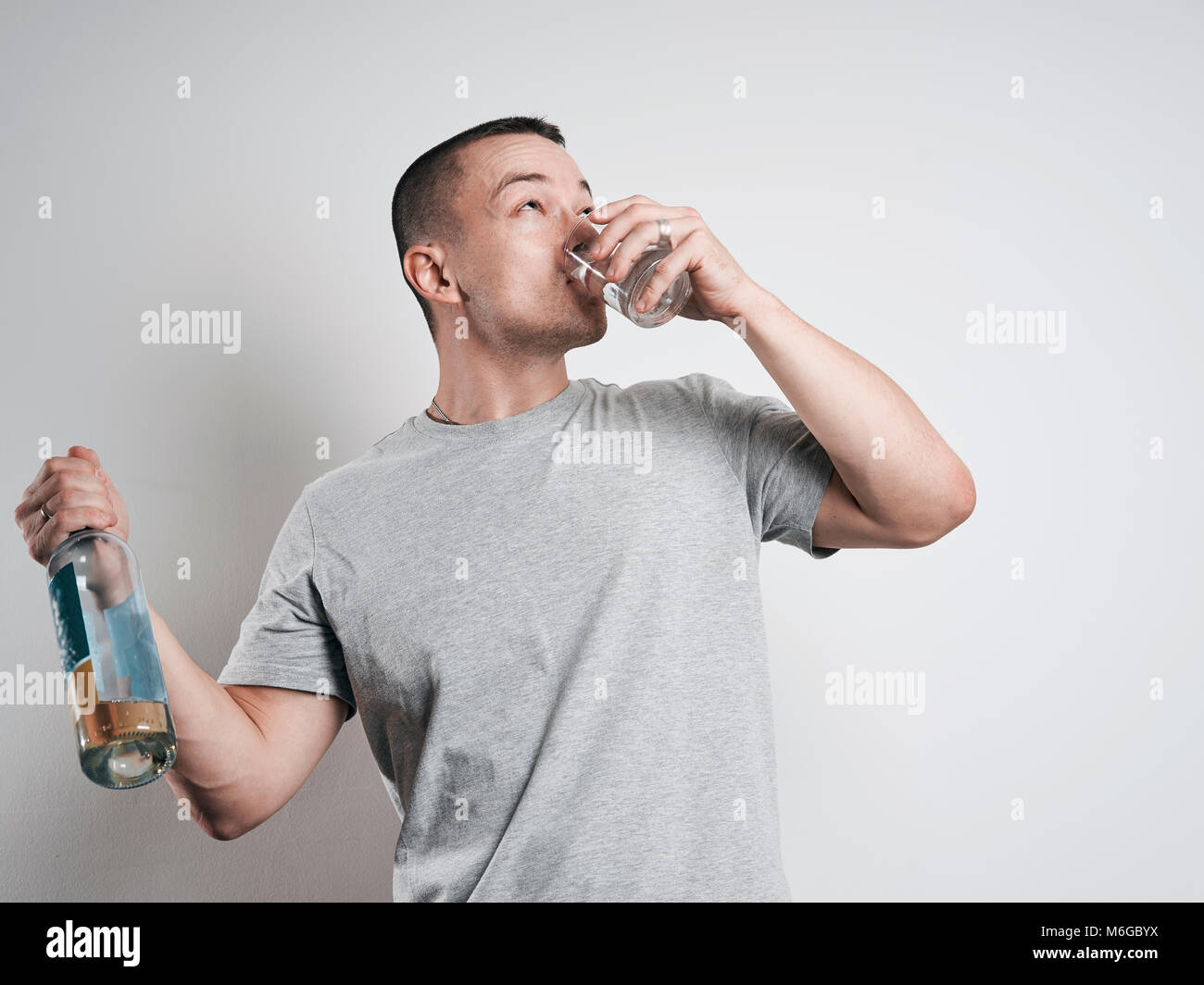 Divertenti uomo ubriaco con una bottiglia su sfondo bianco Foto Stock