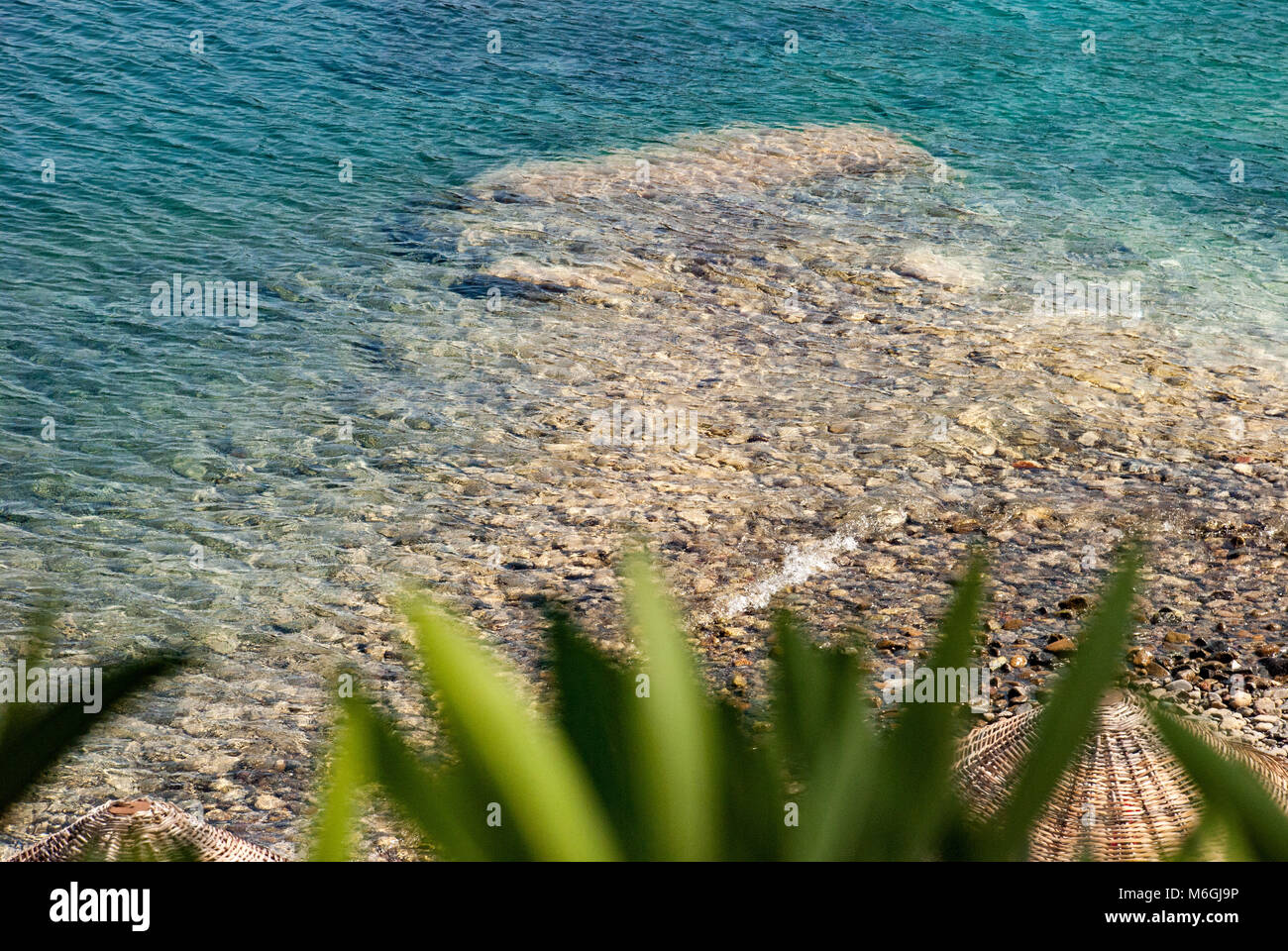 I ciottoli lisci e multicolore coprono la spiaggia di una spiaggia tranquilla, offrendo un'esperienza tattile unica Foto Stock