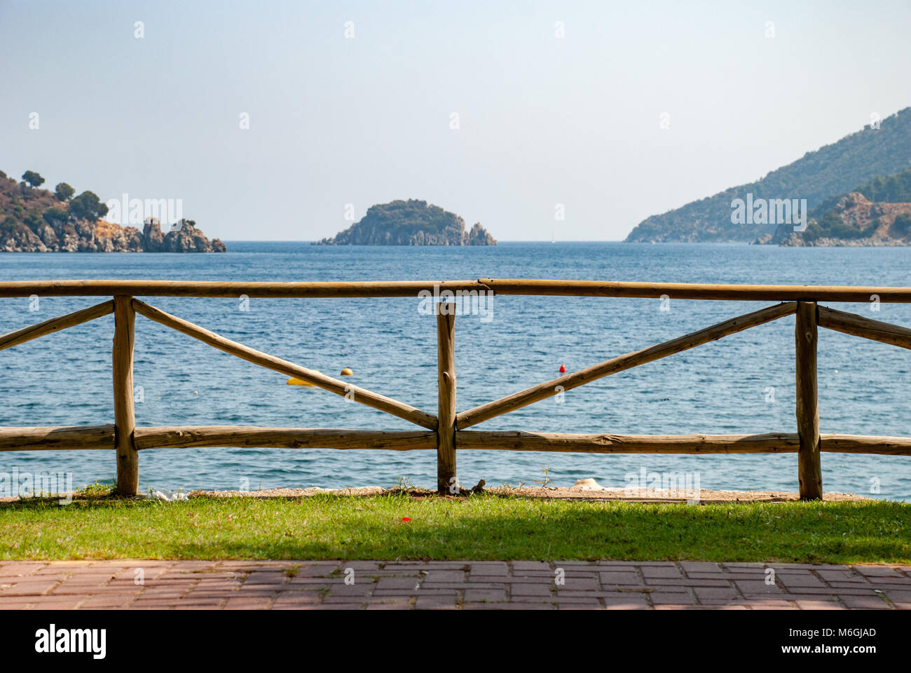 La pittoresca recinzione in legno è allineata a un tranquillo sentiero a piedi sulla riva del mare, che offre vedute panoramiche Foto Stock