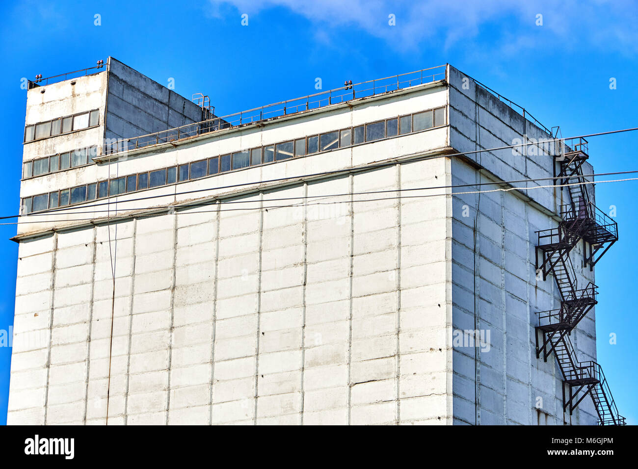 Edificio a silo in cemento con scala antincendio su facciata bianca contro il cielo blu Foto Stock