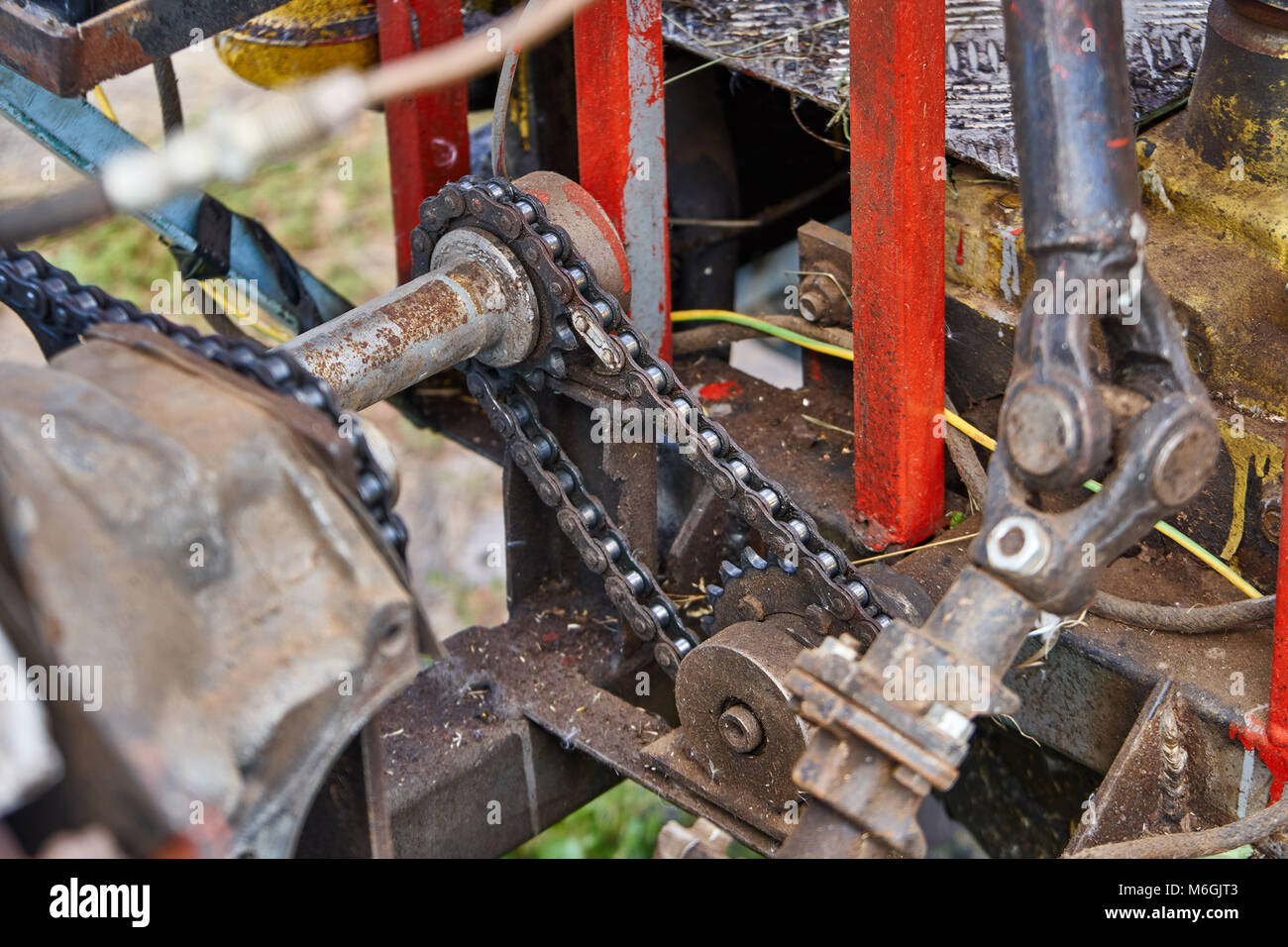 Grande trattore di potenza fatto in casa di colore rosso brillante che utilizza dettagli e fili di altri trattori. Motore con tubi e fili non chiusi in primo piano Foto Stock
