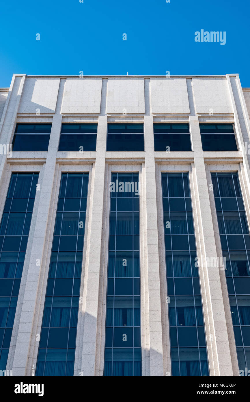 Edificio moderno con linee pulite e vetro riflettente sullo sfondo di un cielo blu luminoso. Architettura contemporanea Foto Stock