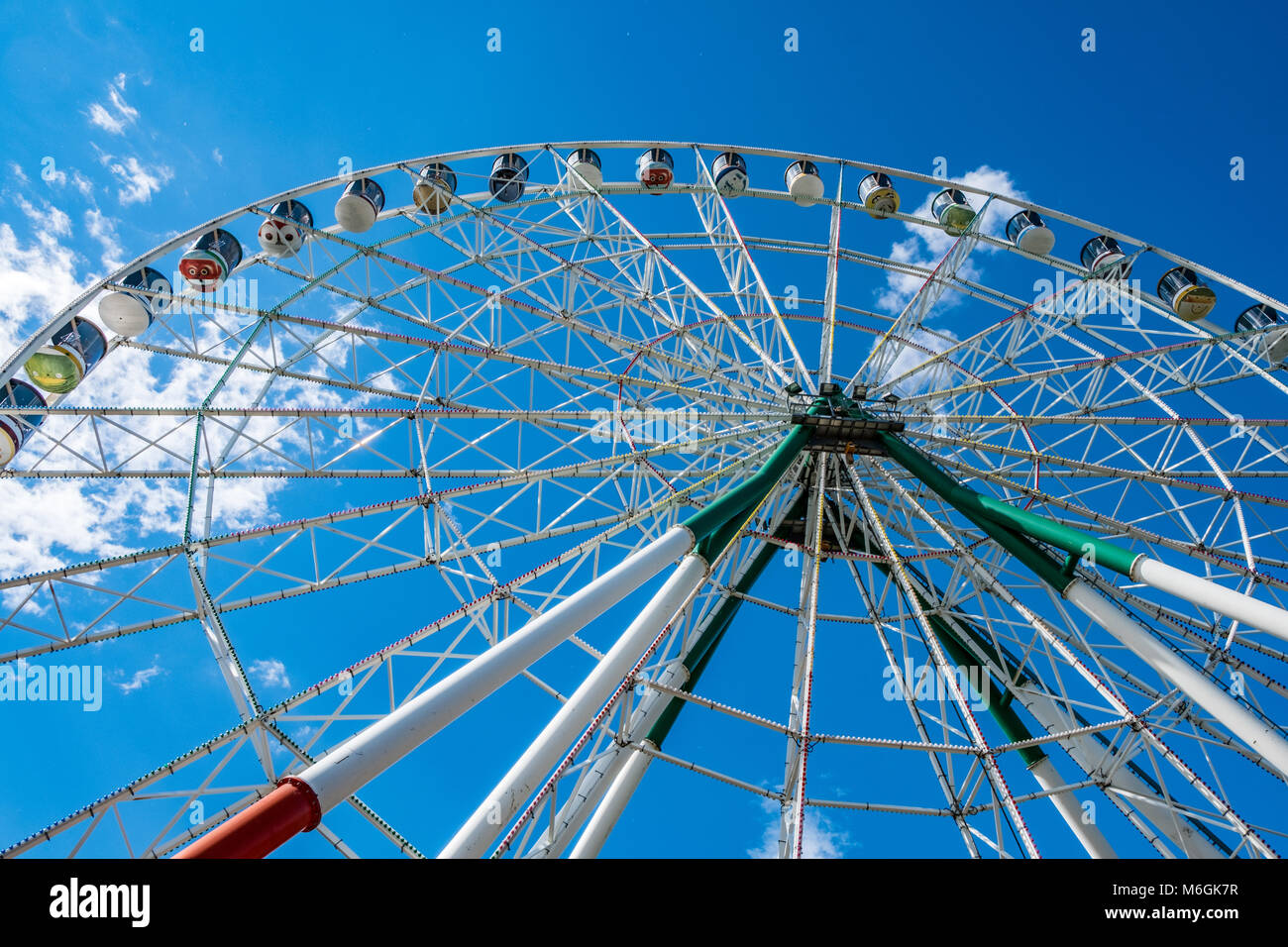 Enorme ruota panoramica contro il cielo nuvoloso nel parco divertimenti con vista dall'angolo basso Foto Stock