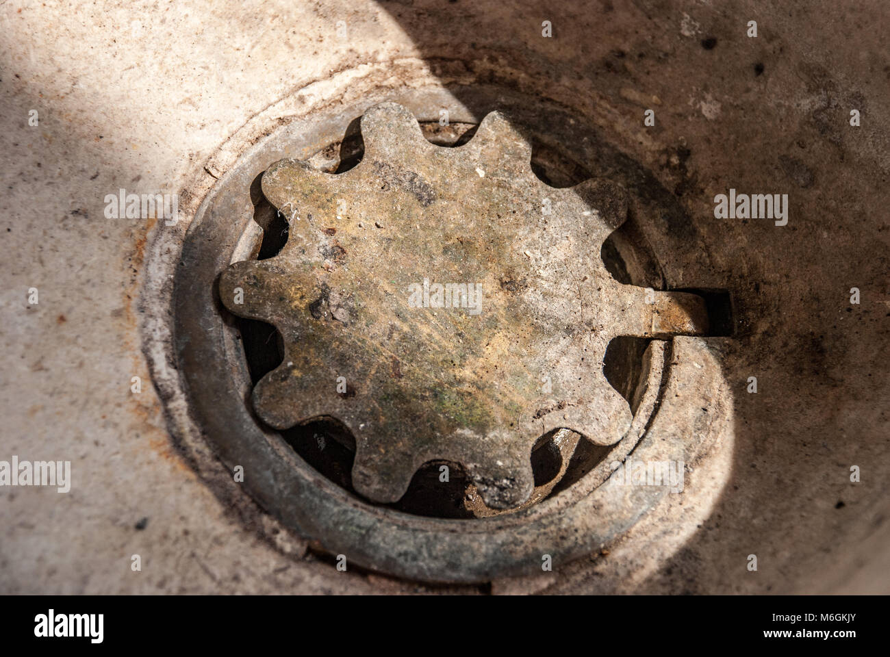 In ghisa a foro di pozzo con un coperchio in un lavandino in pietra Foto Stock
