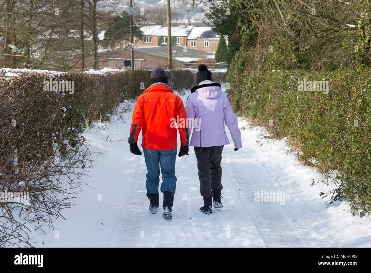 Matura in bright abbigliamento outdoor a piedi su un paese nevoso lane. Foto Stock