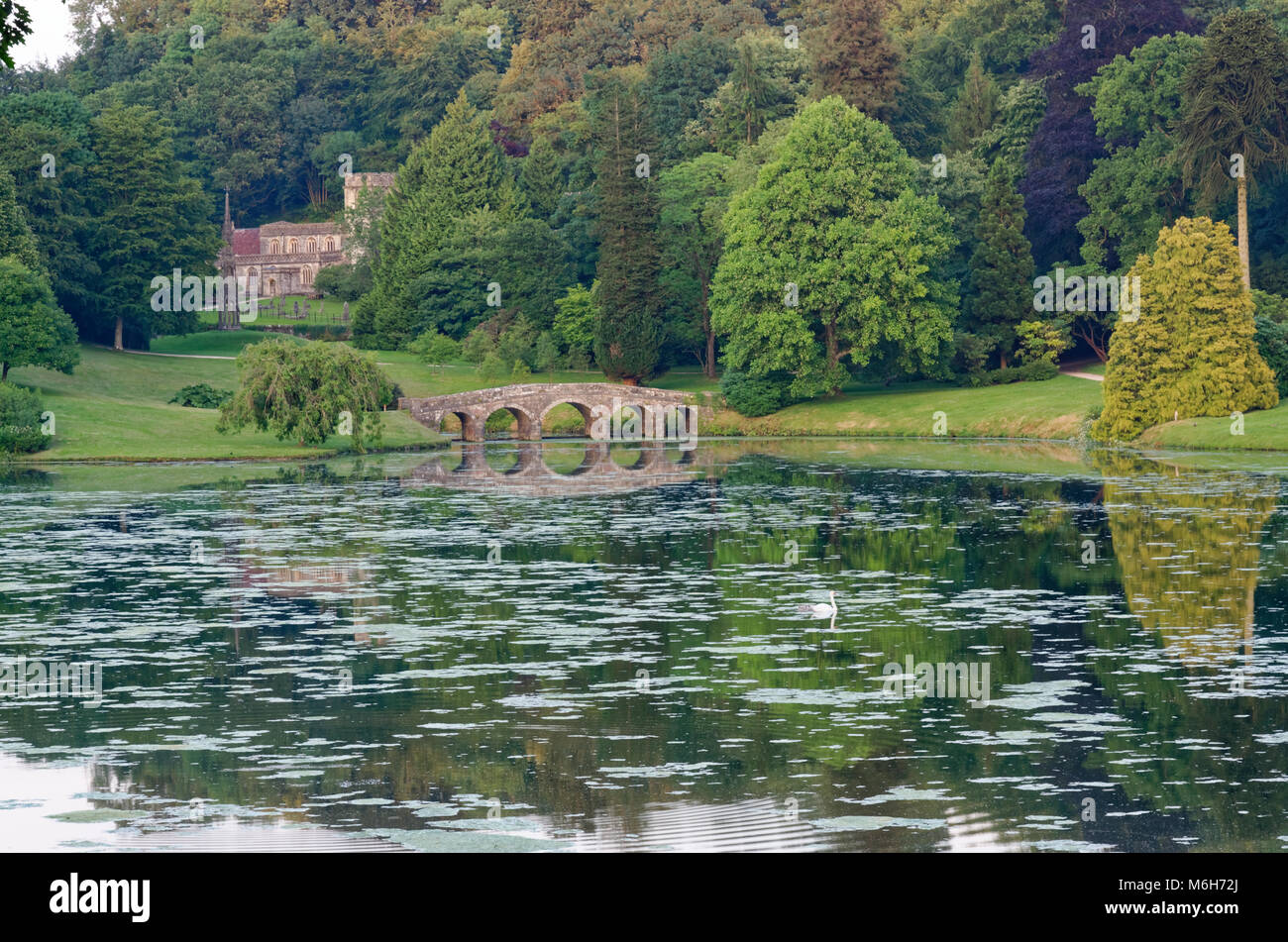 Guardando attraverso la Stourhead Garden lago al ponte palladiano e la chiesa di San Pietro Foto Stock