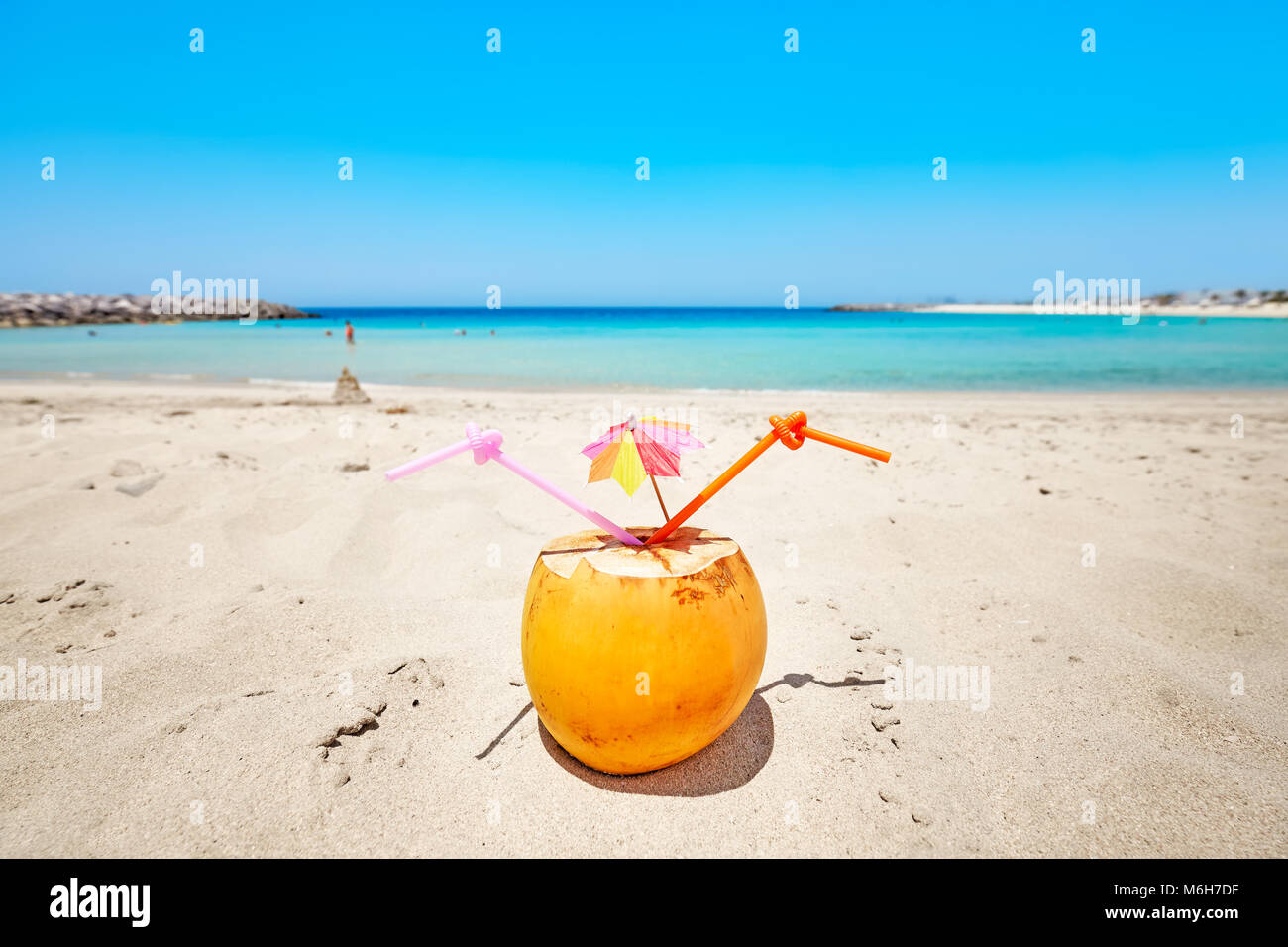 Noce di cocco con ombrello coloratissimo e due cannucce su una spiaggia, vacanze estate concetto, il fuoco selettivo. Foto Stock