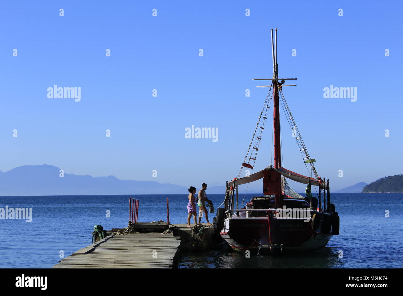 Paio di salire a bordo di una barca a vela ormeggiata al molo di Ilha Grande, Brasile Foto Stock