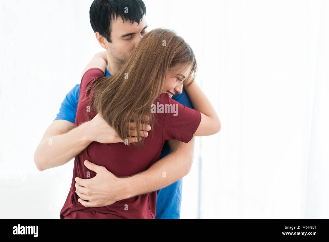 Ritratto di Asian amante o giovane abbracciando e baciando con azione sorridente in camera da letto a casa, coppia romantica concetto. Foto Stock