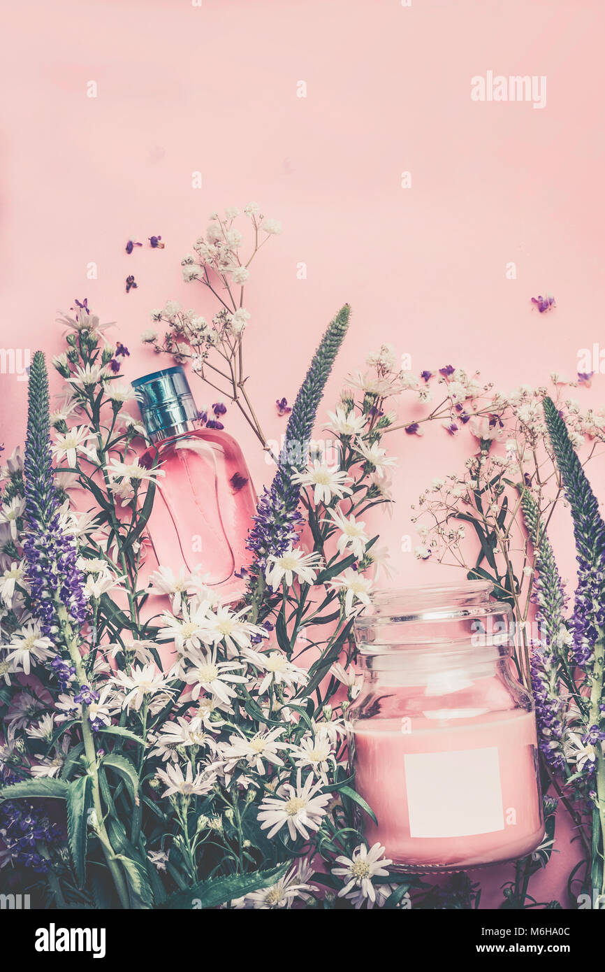 Cosmetici naturali a base di erbe con foglie e fiori, etichetta vuota per il branding mock-up sul rosa pastello sfondo, vista dall'alto con spazio di copia Foto Stock