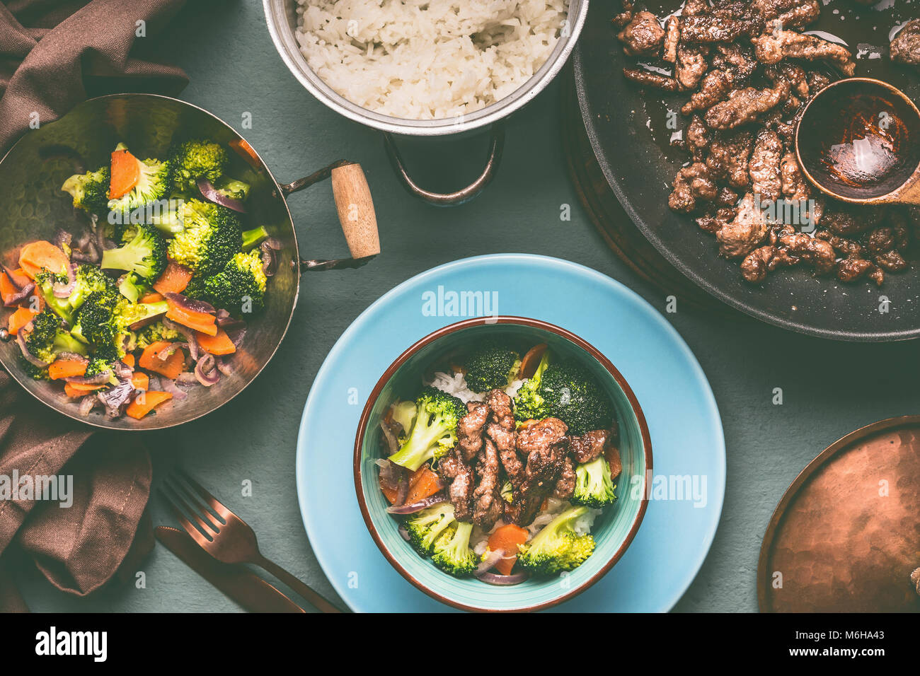 Una sana nutrizione bilanciata piatto in vasi e ciotole con carne di manzo e verdure al vapore e riso su sfondo tabella con piastra e posate, vista dall'alto Foto Stock