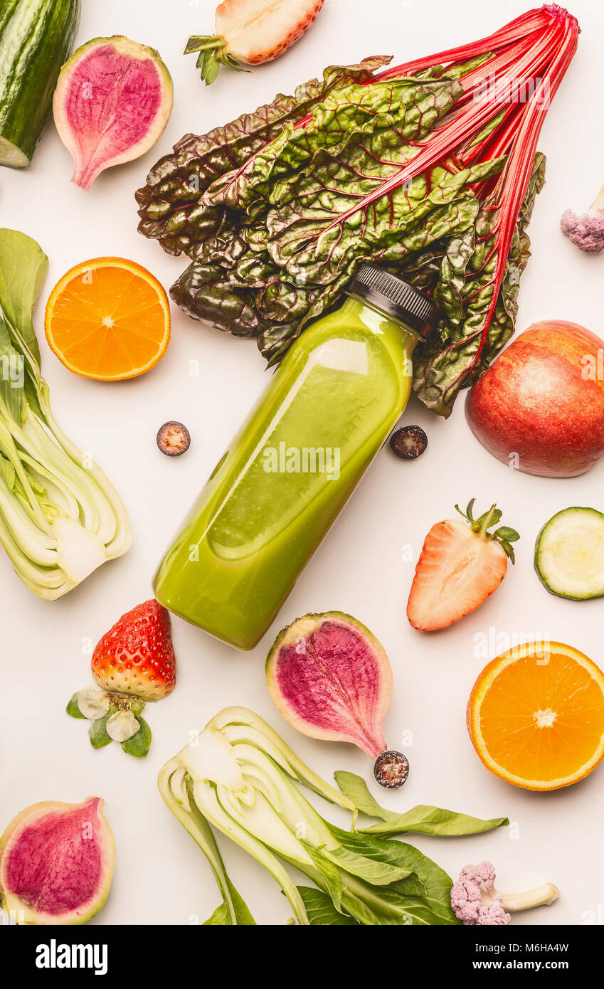 Frullato verde bottiglia con sani frutti e verdure ingredienti bianco su sfondo scrivania, vista dall'alto, piana, laici verticale. Pulire e detox, peso l Foto Stock