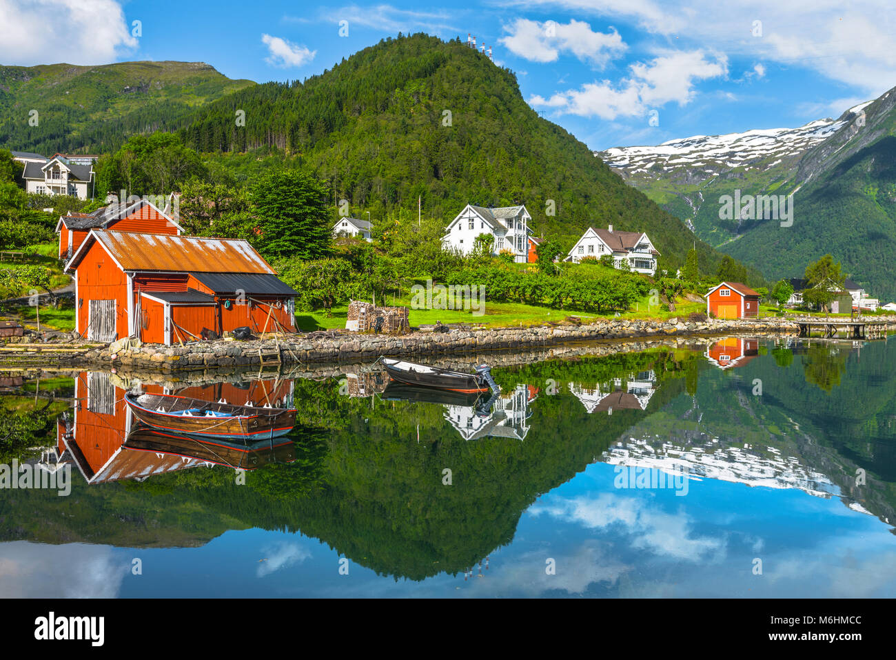 Barche e pescatori rosso capanna, Norvegia, riva del mare e la baia di Balestrand con il mirroring di neve montagne, Esefjorden, Sognefjorden Foto Stock