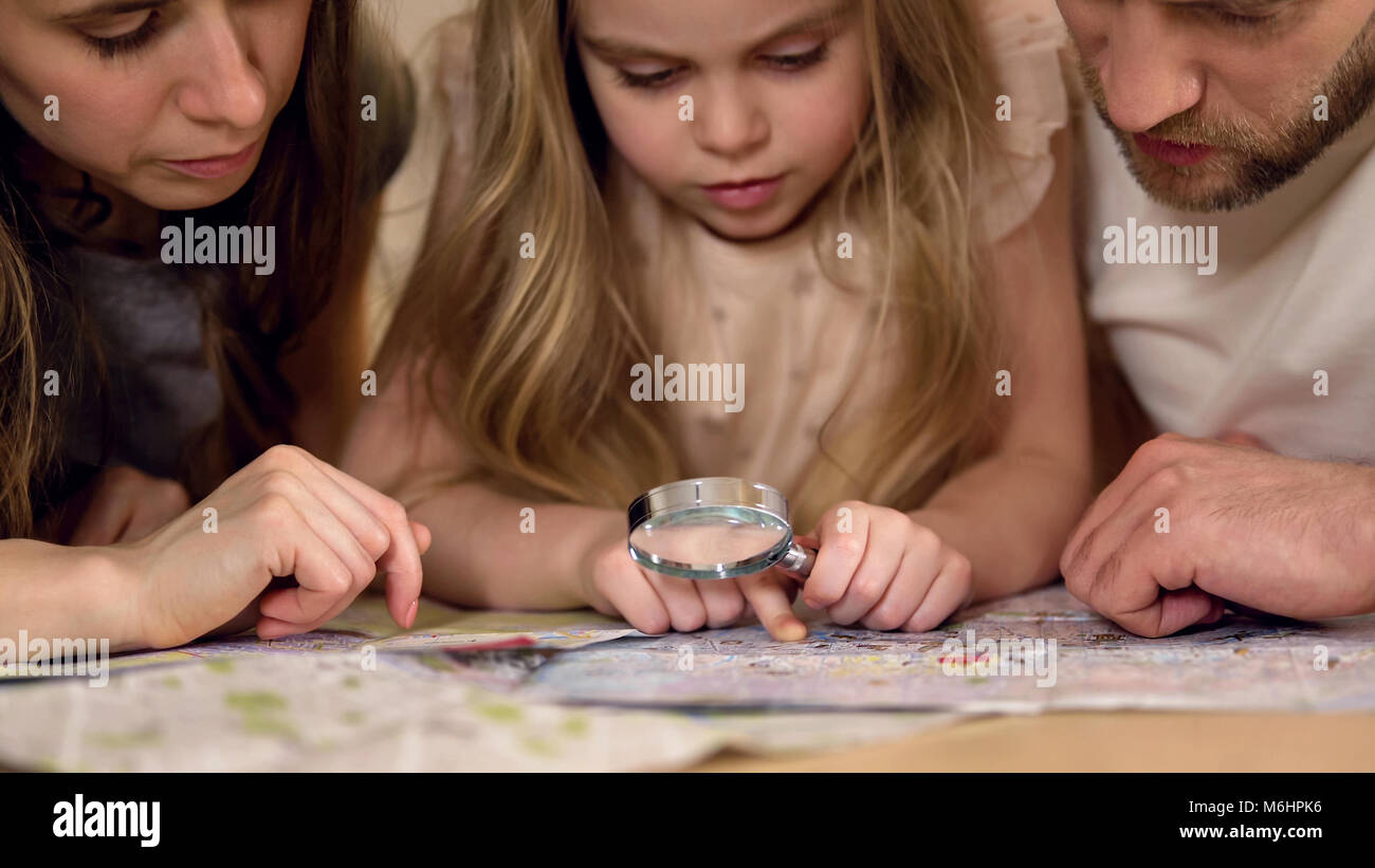 I genitori imparare la geografia con la figlia, studiare mappa attraverso la lente di ingrandimento Foto Stock