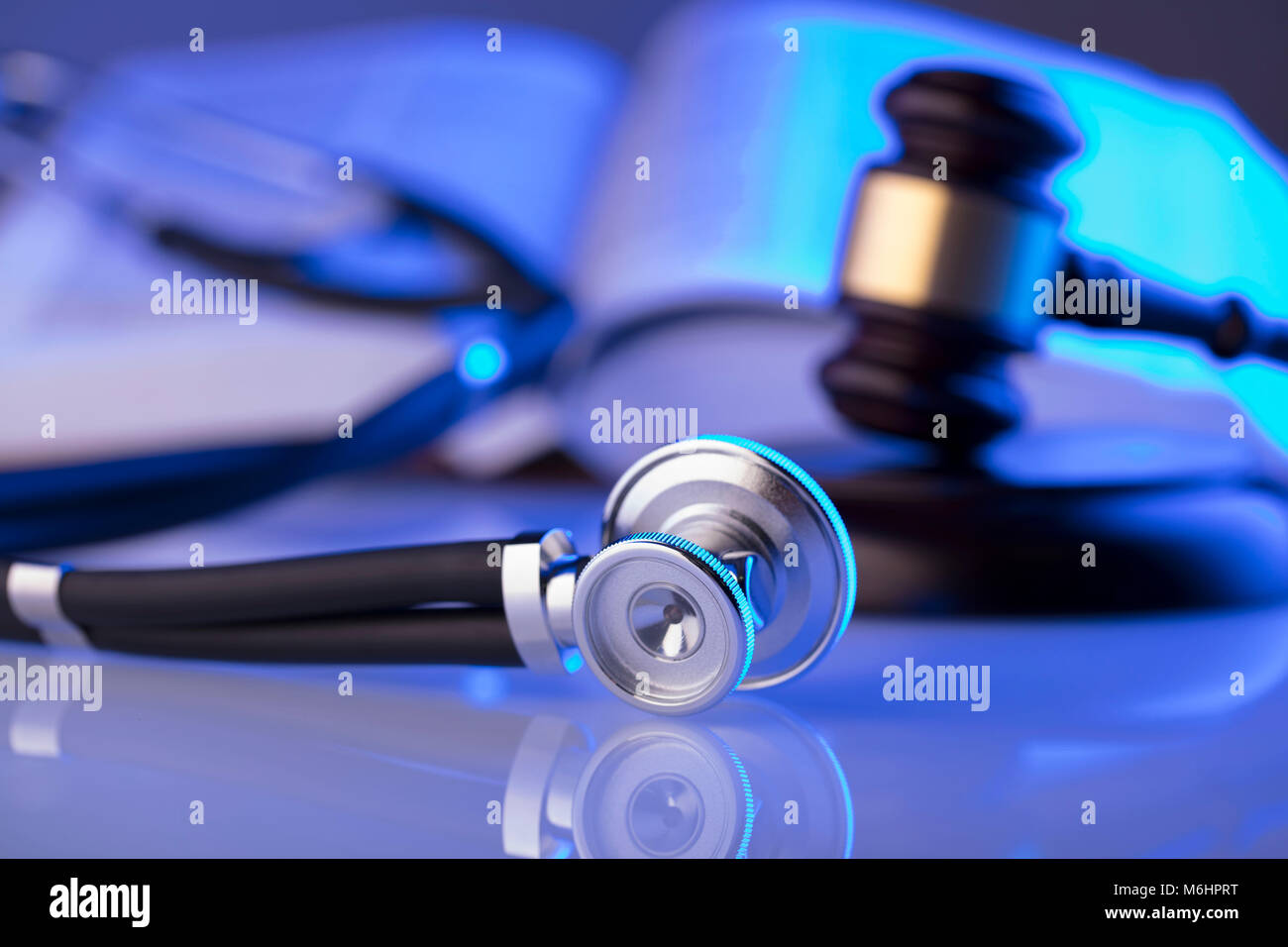 La legge medica concetto. Martello, uno stetoscopio luce blu. Luogo fort testo. Foto Stock