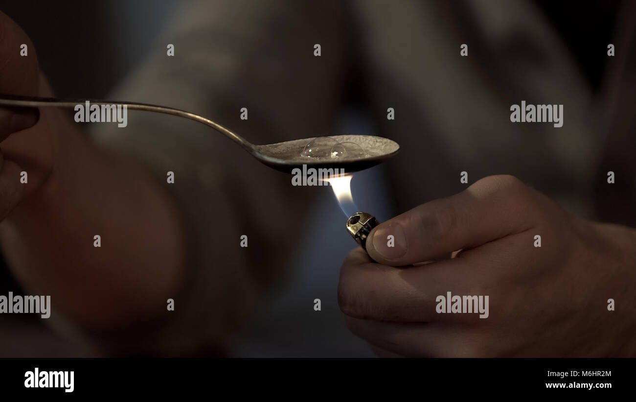 Uomo di riscaldamento dose di eroina in cucchiaio con più leggero, maschio  tossicodipendente la preparazione di dose Foto stock - Alamy