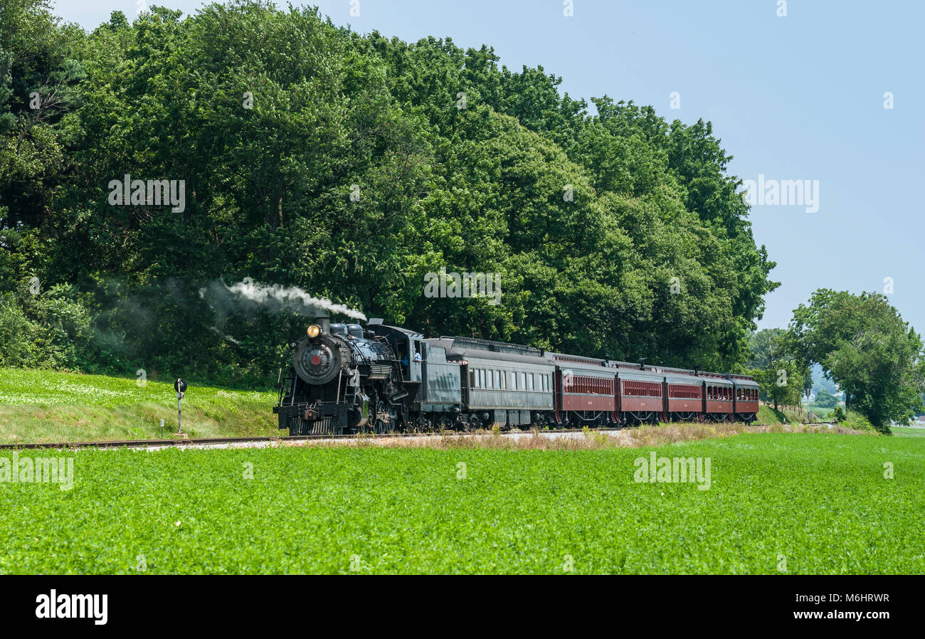 Treno a vapore motore con autovetture passeggeri lasciare spento in una calda giornata estiva Foto Stock Treno a vapore motore con autovetture passeggeri lasciare spento in una calda giornata estiva Foto Stock