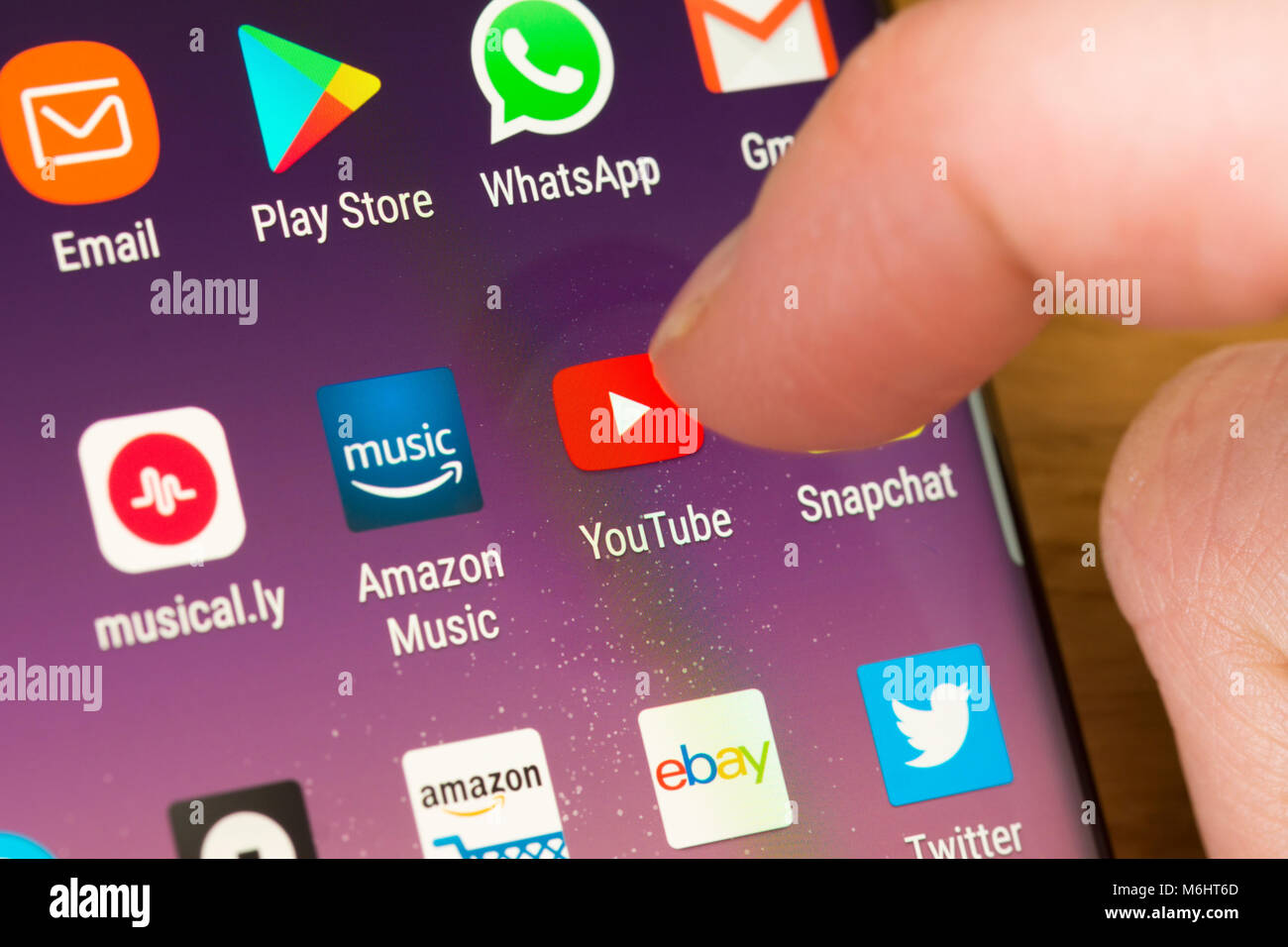 Primo piano dell'app YouTube su uno smartphone selezionato con il dito di una donna che punta verso l'app sul schermo del telefono cellulare Foto Stock