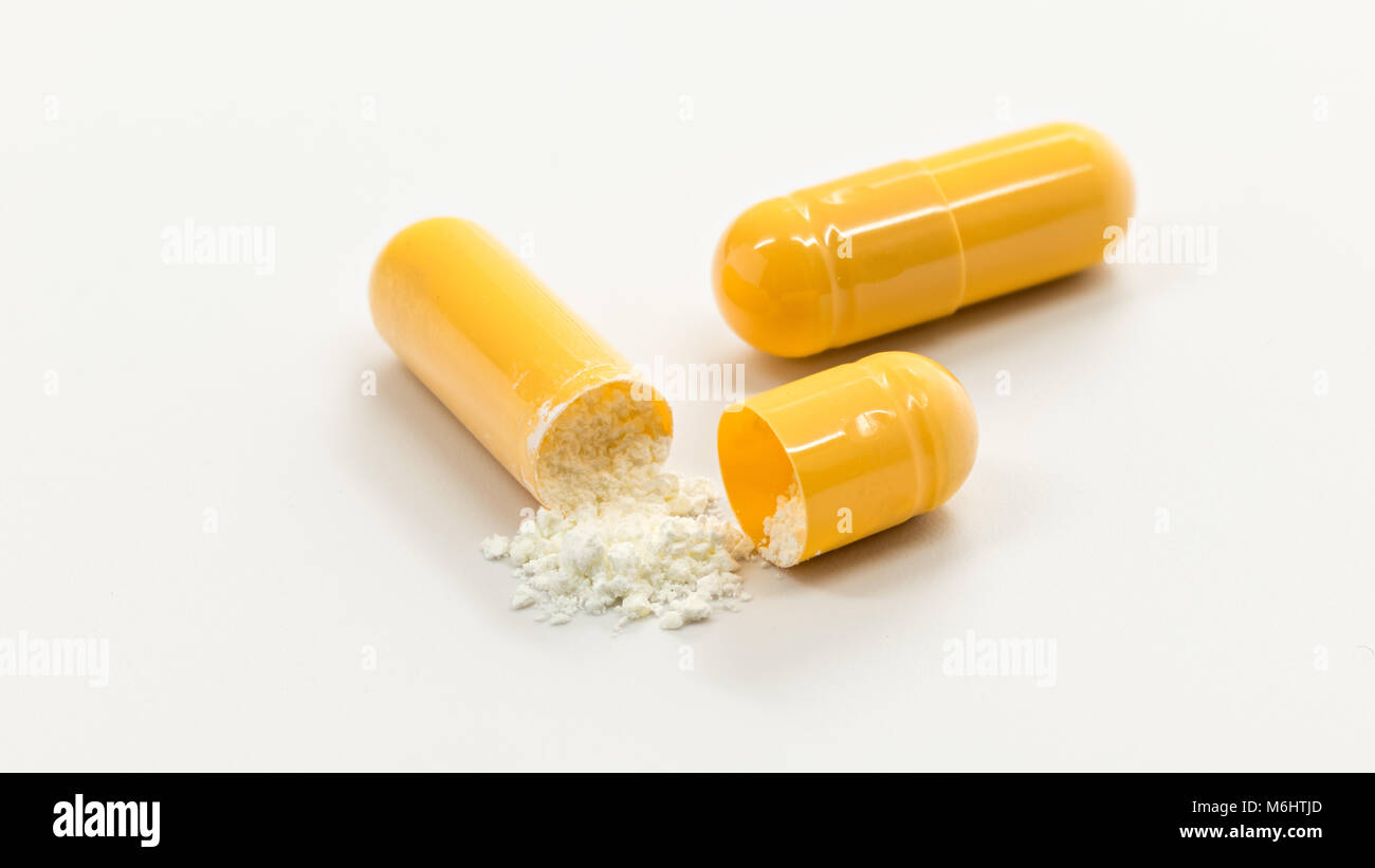Due giallo capsule a freddo con uno rotto aprire per vedere la medicina Foto Stock