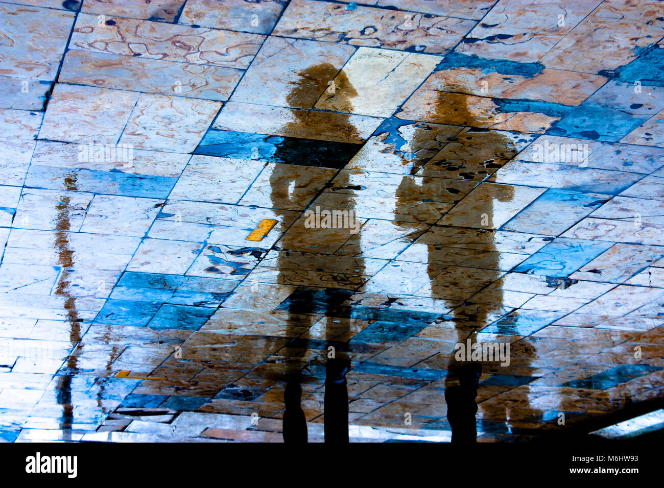 Silhouette di riflessione di due giovani donne a camminare sul marciapiede della città in un giorno di pioggia con colori vibranti Foto Stock