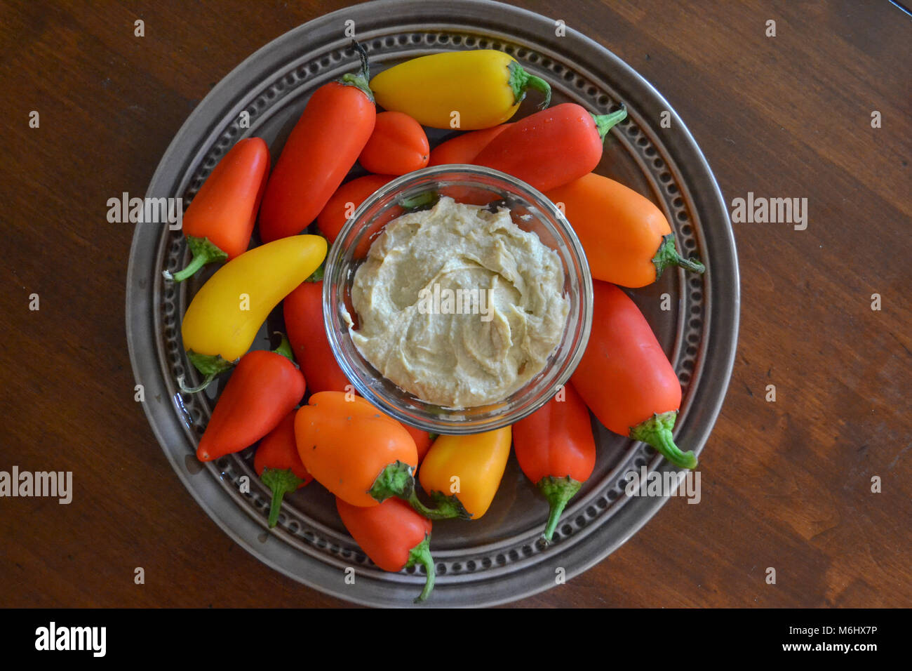 Dolce croccante di colore rosso, giallo e arancione mini peperoni servito con panna hummus. Gourmet snacking sano non è mai stato così bello. Foto Stock