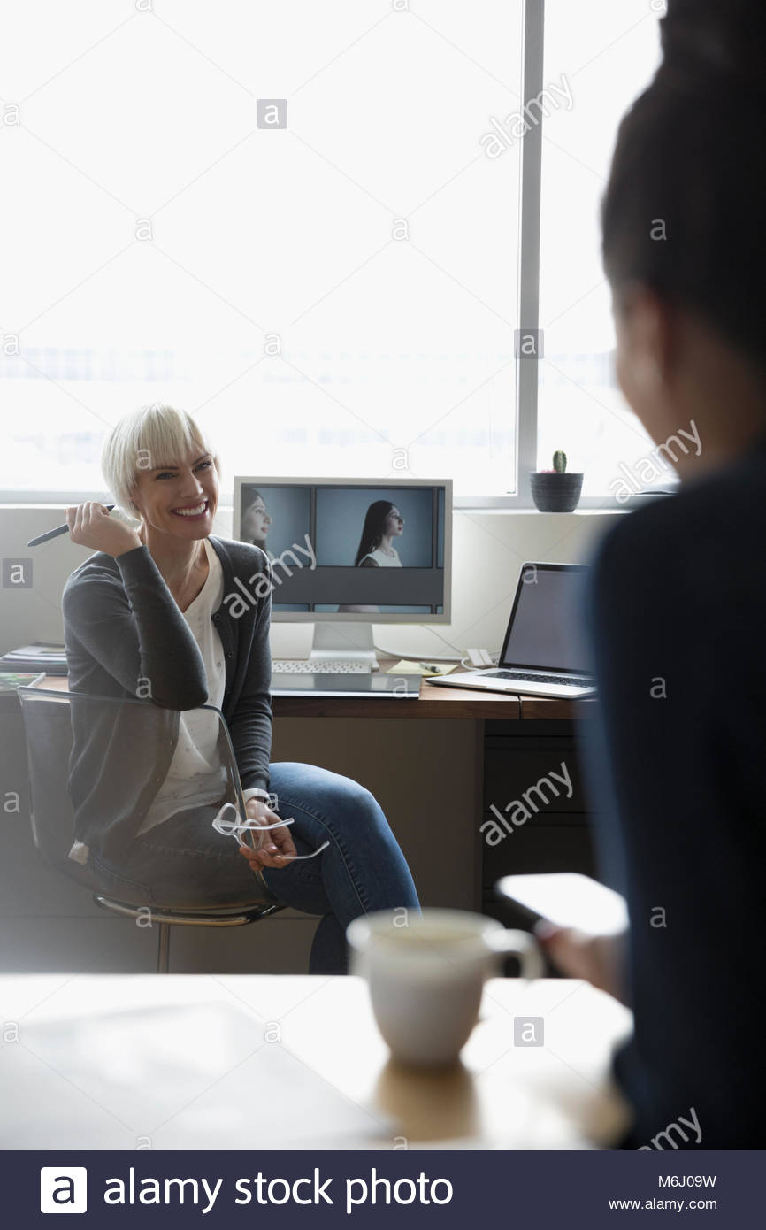 Femmina editor foto al computer parlando a un collega Foto Stock