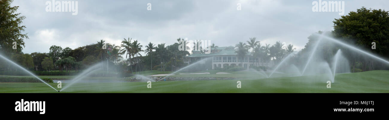 Tropical bellissimo campo da golf scenic panorama, clubhouse privato, palme, lago, soft focus tramite sprinkler misty crea scena tranquilla. Foto Stock