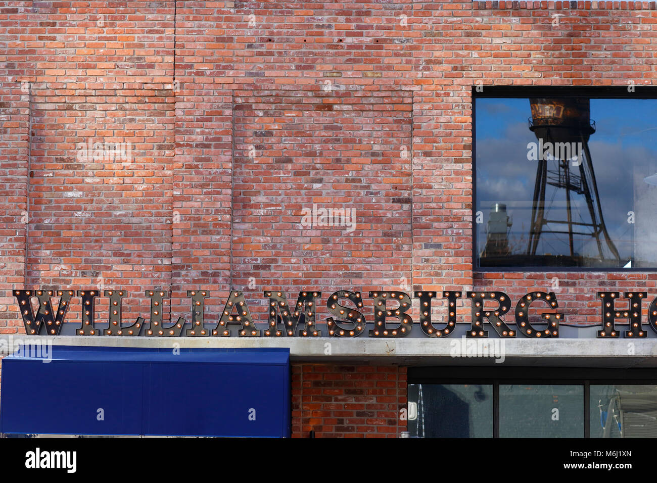 La riflessione di un unico acciaio industriale rooftop nyc serbatoio acqua nella finestra di Williamsburg Hotel, 96 Wythe Ave, Brooklyn, New York. Foto Stock