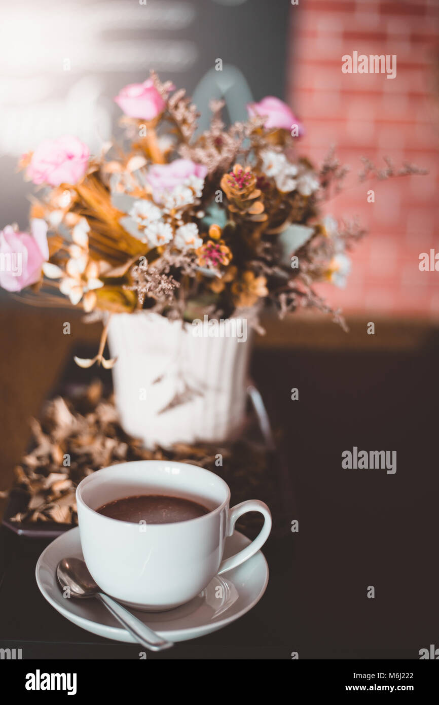 Un bianco tazza di caffè con fiori secchi sulla tavola , colore vintage Foto Stock