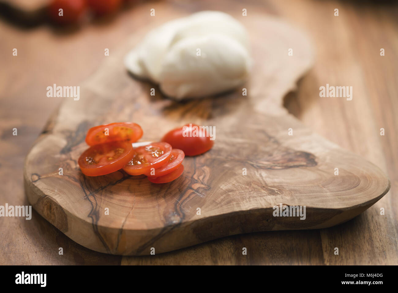 Fette di pomodori ciliegia e mozzarella su pannello di legno Foto Stock