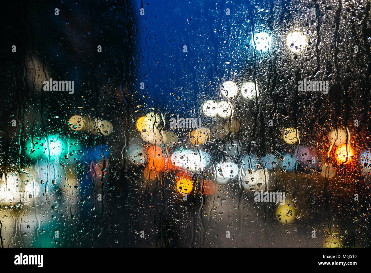 Emotional malinconico sfondo astratto con luci sfocati bokeh in Londra, Regno Unito dietro delle gocce di pioggia in vetro, concentrarsi sulle poche gocce a causa della profondità di campo Foto Stock