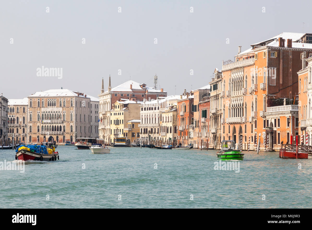 Occupato il traffico delle barche di fronte coperta di neve di palazzi sul Canal Grande, San Polo, Venezia, Veneto, Italia durante il rigido inverno con Si Foto Stock