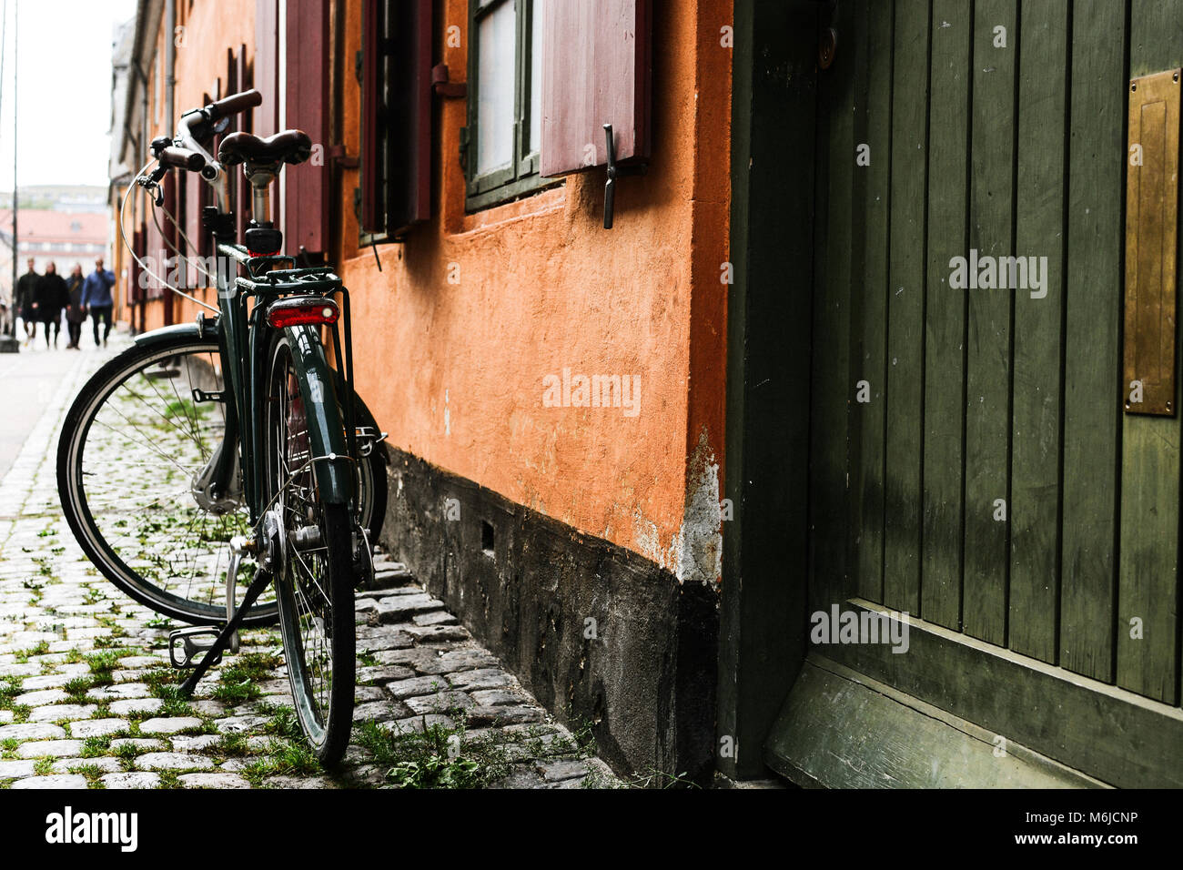 Bicicletta vicino alla parete arancione di vecchi edifici di Copenhagen, Danimarca. Lo stile di Copenaghen, Danimarca bicicletta, strada europeo Foto Stock