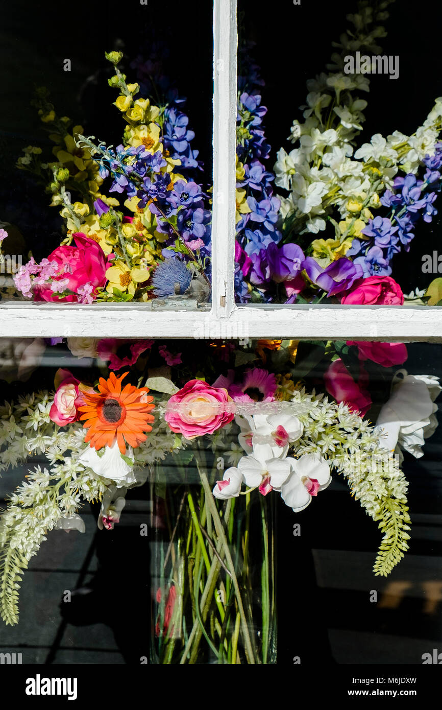 Una sistemazione floreale visibile attraverso una finestra. Foto Stock