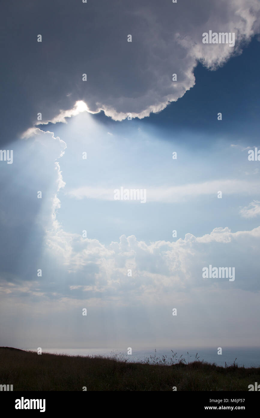 I picchi di sole attraverso una pausa tra le nuvole sopra Baliato di Guernsey, Regno Unito Foto Stock