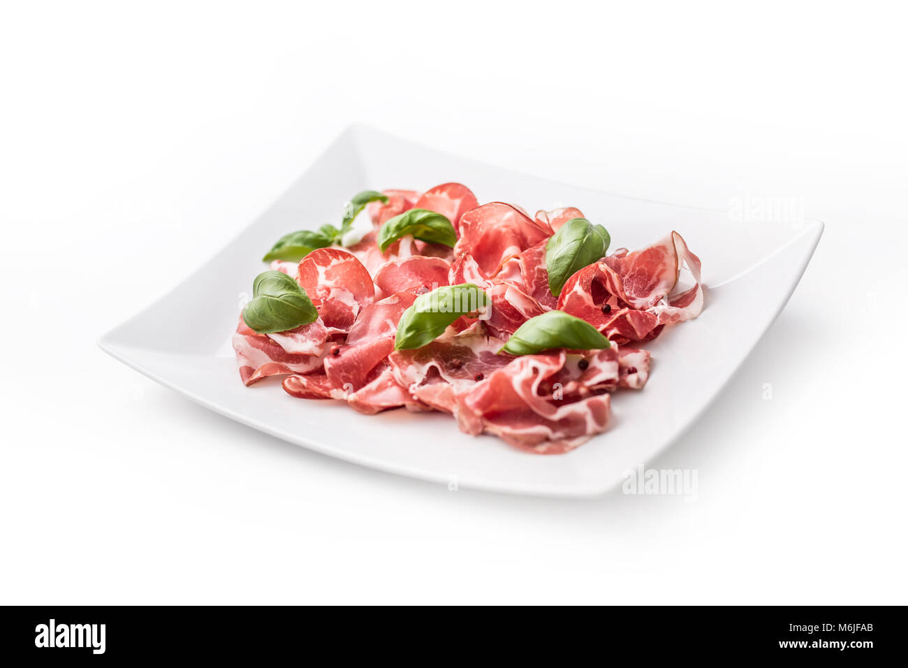 Il prosciutto. Arricciato fette di deliziosi piatti della cucina italiana il prosciutto con il basilico. Foto Stock