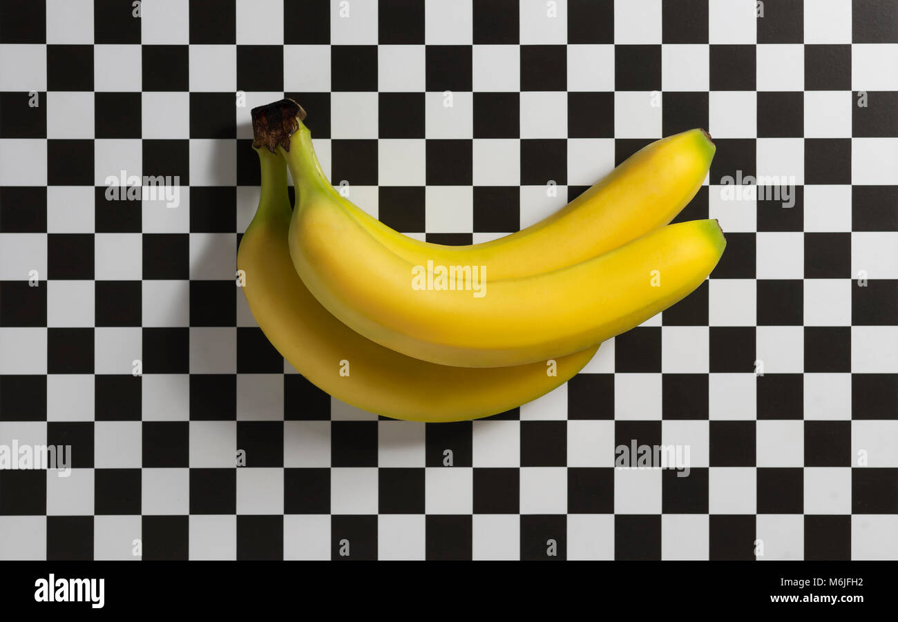 Tre le banane su un fondo a scacchi ancora vita dell'immagine. Foto Stock